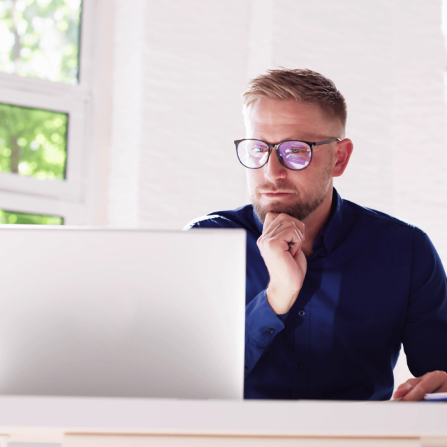 A man sits in front of a computer, deep in thought during his employee coaching session