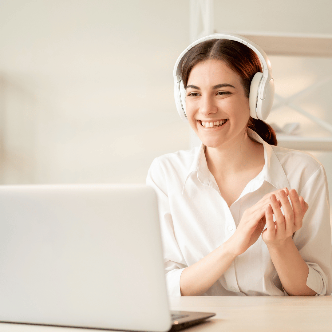 A woman smiles at her laptop during her employee coaching session